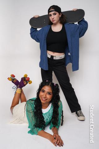 Image of a student photoshoot with two student models. One wearing sporty clothes, backwards hat and a skateboards over their shoulder. The other model is laying down on their stomach with roller skates on their feet and a smile on their face.